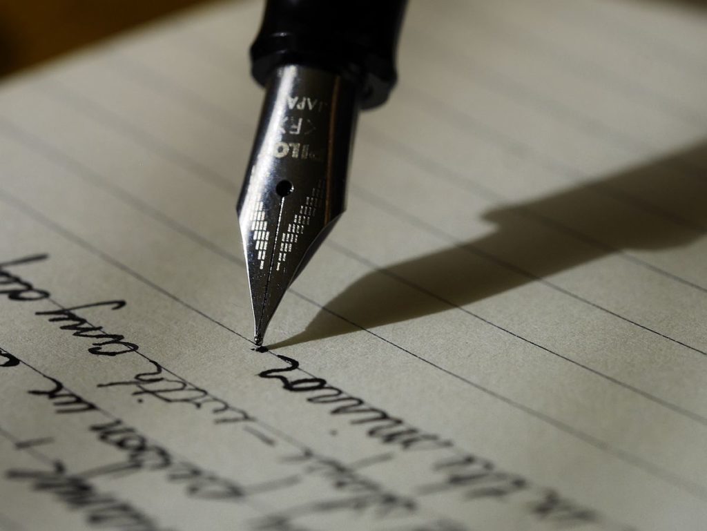 As part of effective business writing, a fountain pen writes on a lined sheet of paper in black ink.
